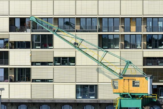 Nahaufnahme der Fassade mit Einblick in Büro und Wohnungen, davor steht ein original Lastenkrahn