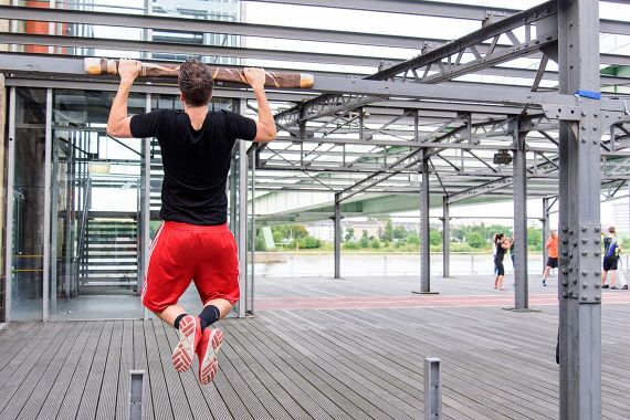 Der Rheinauhafen wird zum Outdoor-Gym. Sportler macht Klimmzüge an Metalpfeiler